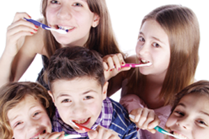 5 children brushing their teeth together and practicing good dental hygiene