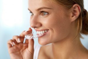 Women placing invisalign tray in her mouth
