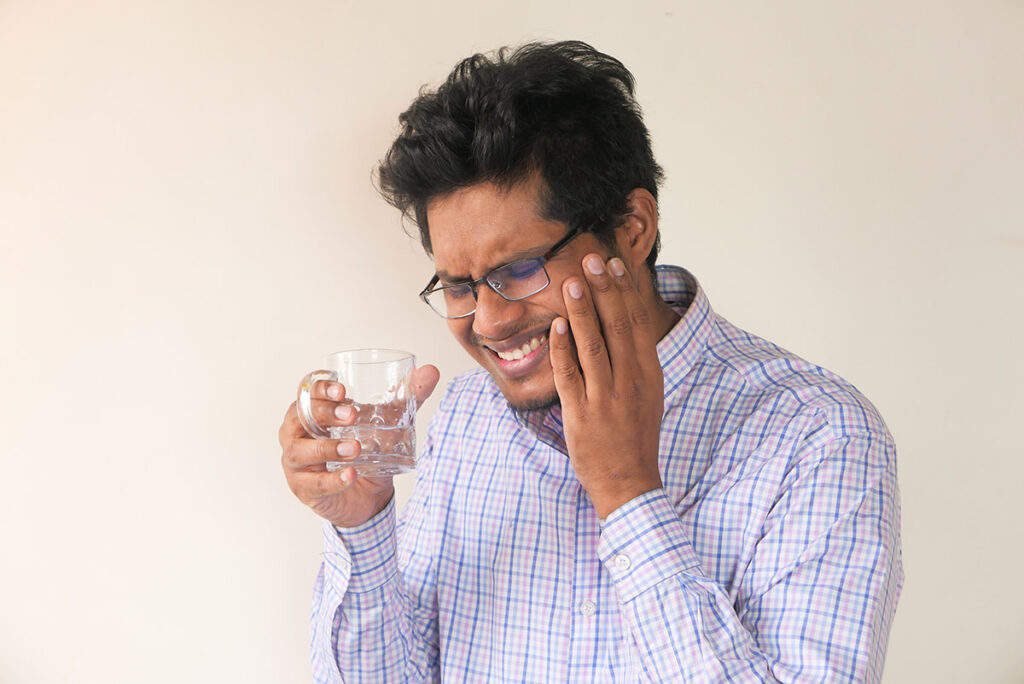 Man with sensitive teeth drinking water