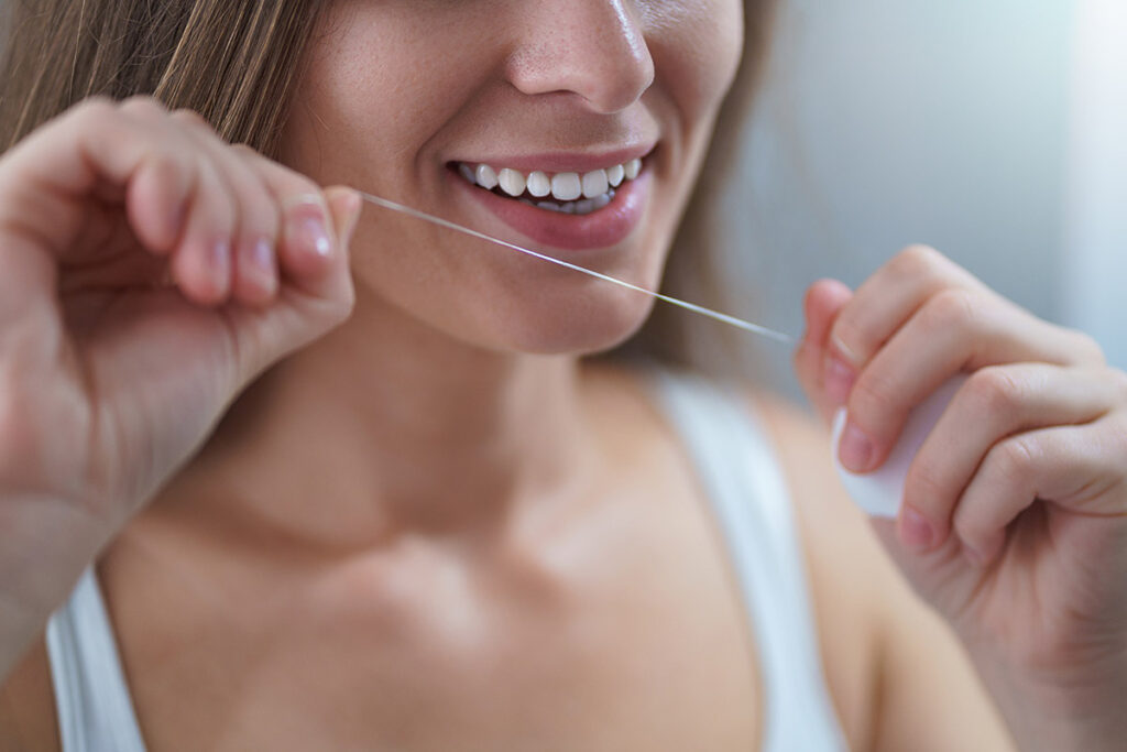 Woman using floss to floss her teeth